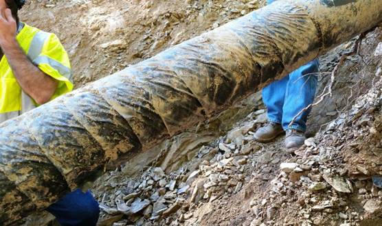 pipe showing signs of wrinkling caused by soil stress on a film backed tape